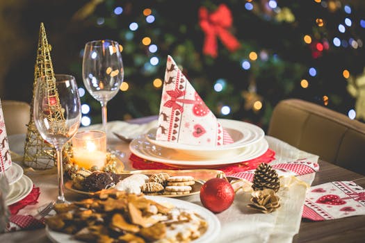 Table festive décorée pour Noël avec plats gourmands, bougies, verres et décorations de saison.